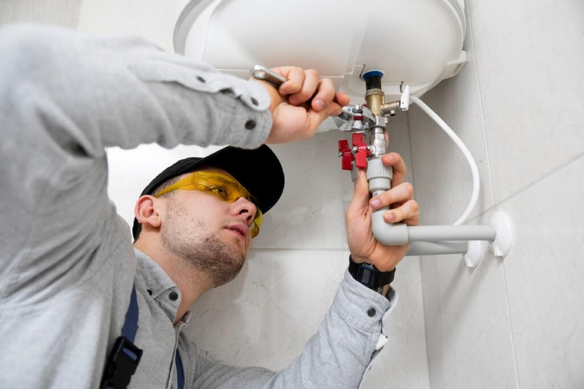 Technicien resserrant les raccords d'un chauffe-eau